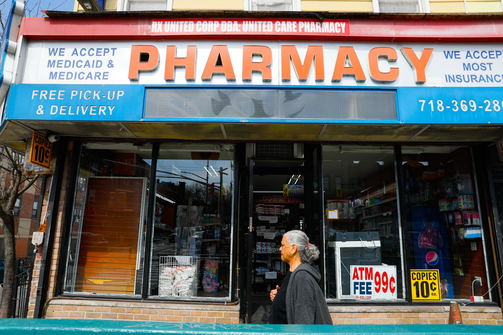 A woman walks past a pharmacy.