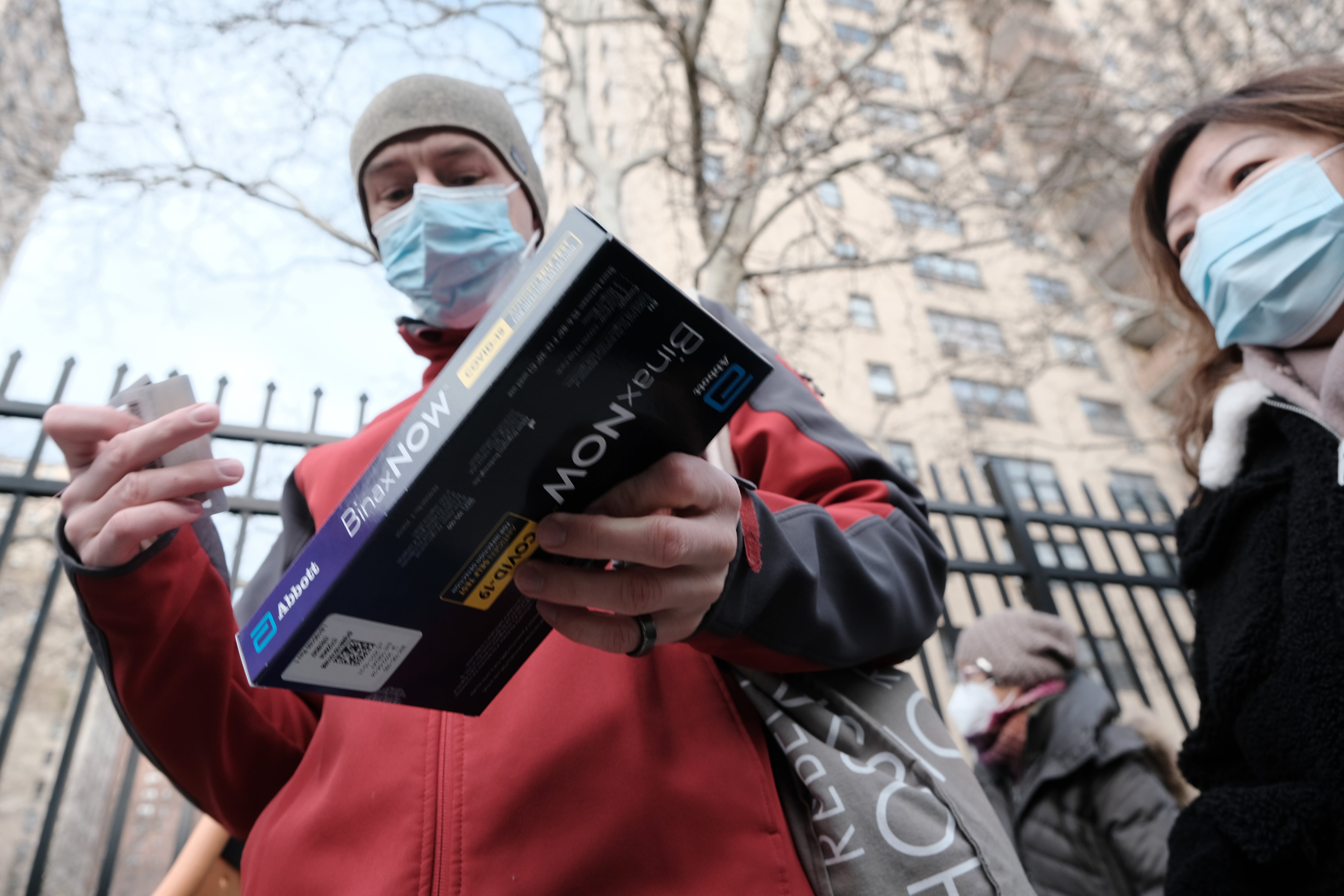 People standing in line outside in New York City receive home Covid tests.