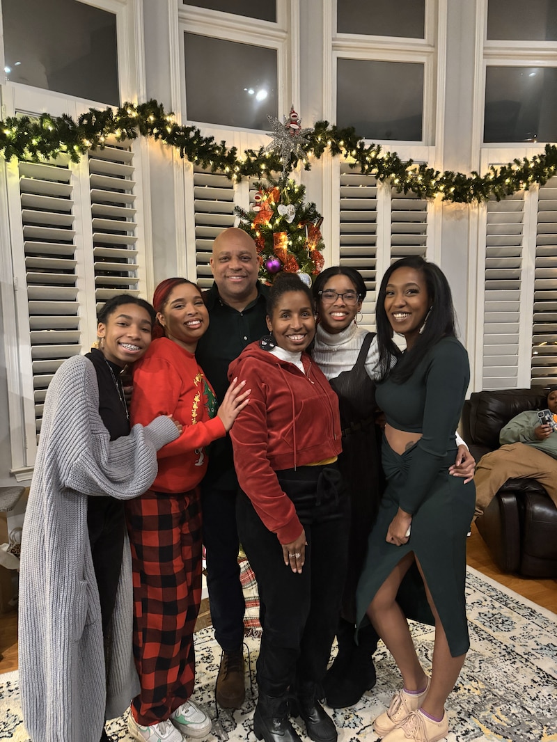 A family stands in front of Christmas decorations.