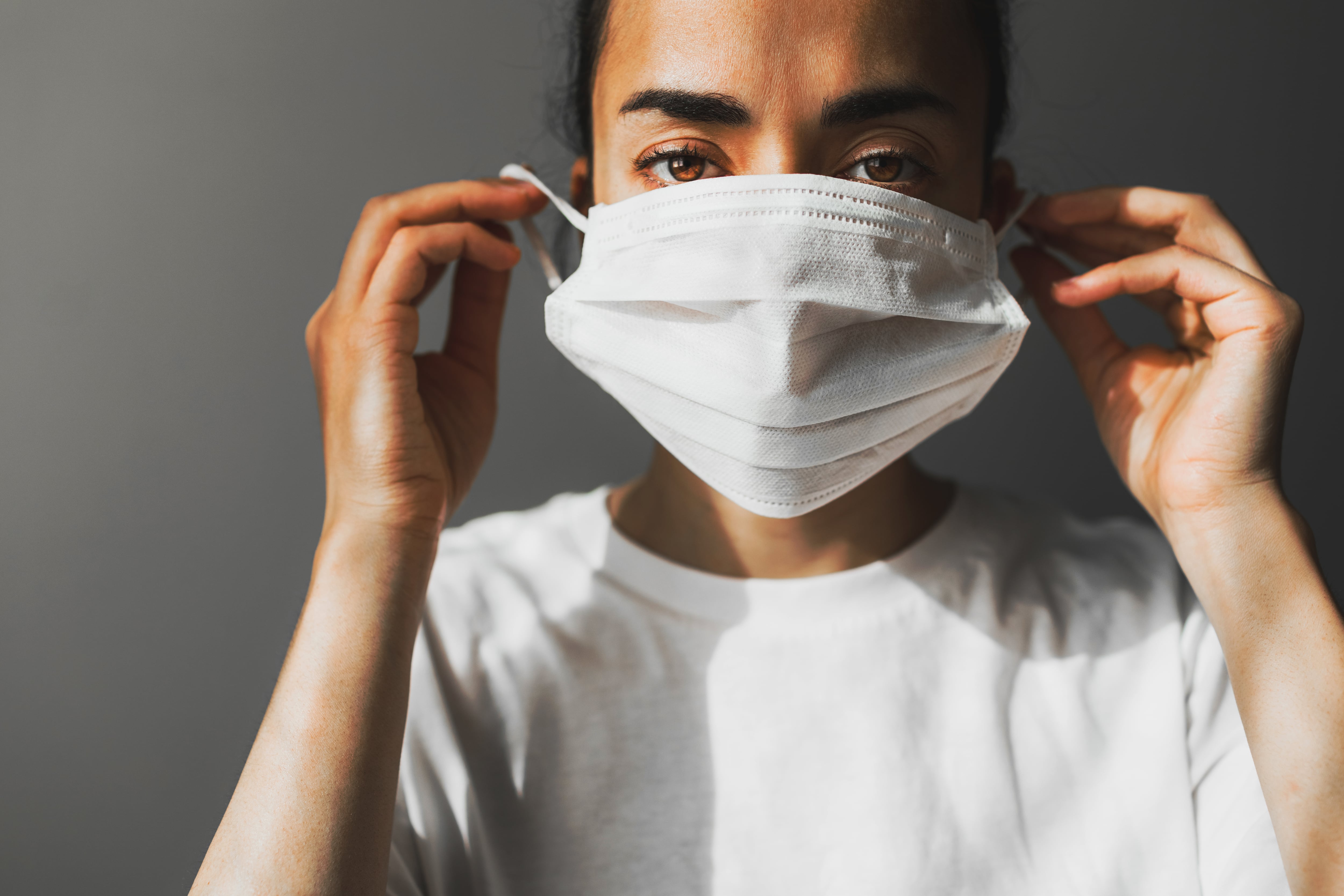 A woman puts on a surgical mask.