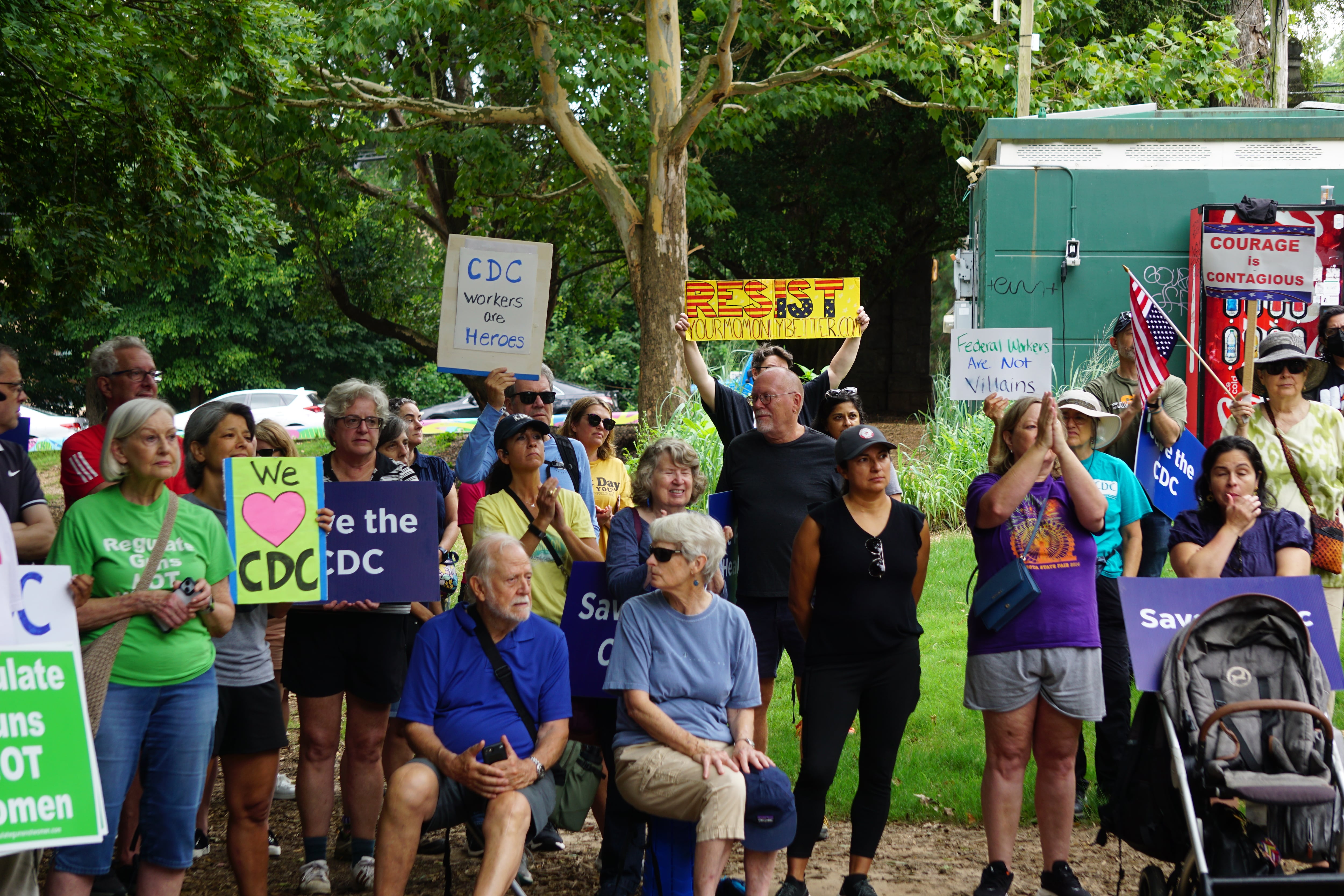 People hold signs in support of the CDC at an outdoor rally.