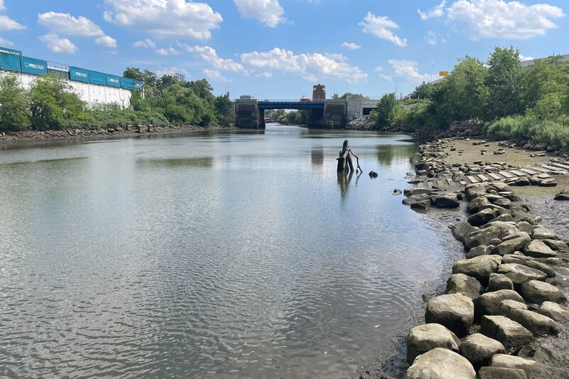 A person stands in the polluted water of the Bronx River.