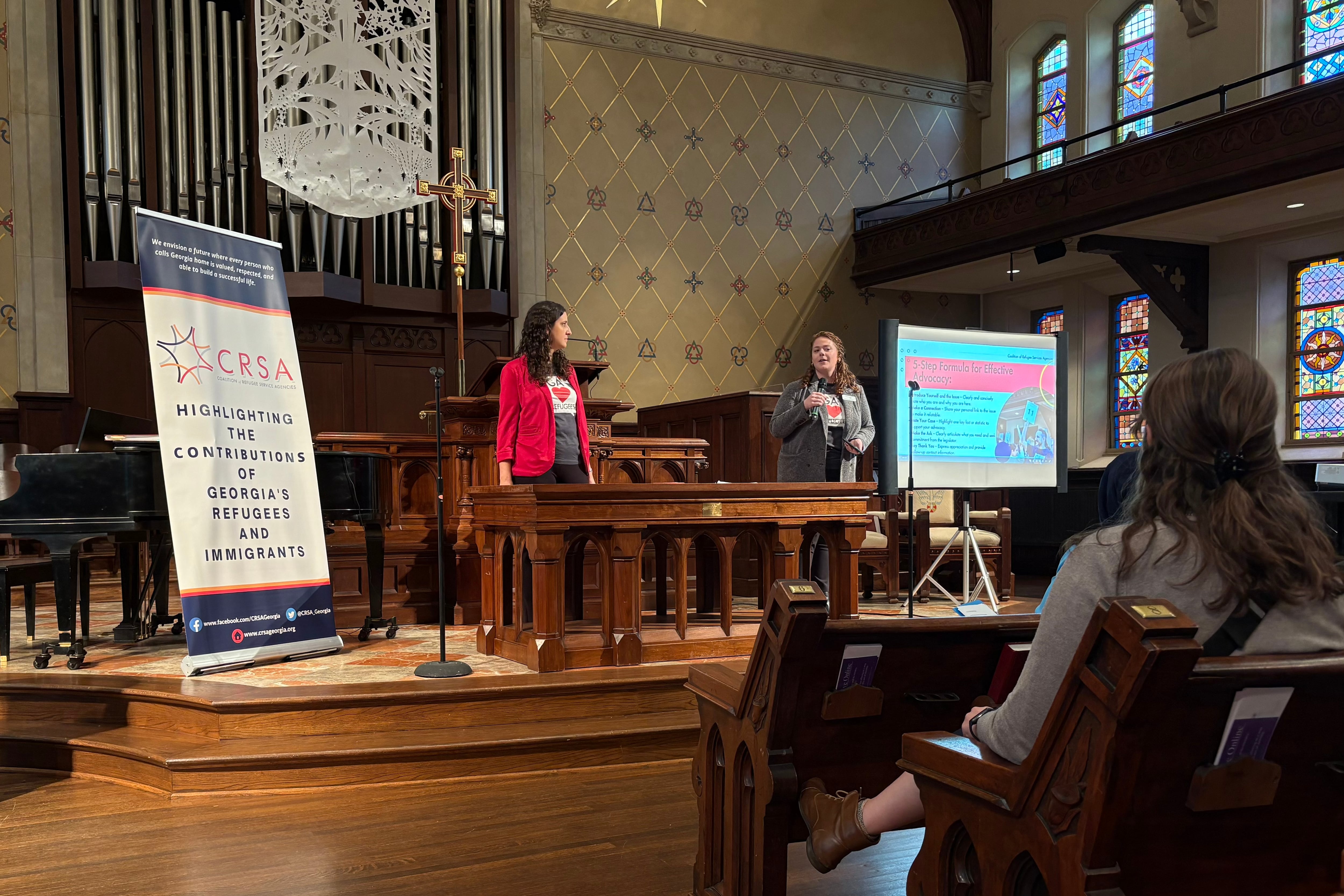 Two women speak at a podium in a church sanctuary.