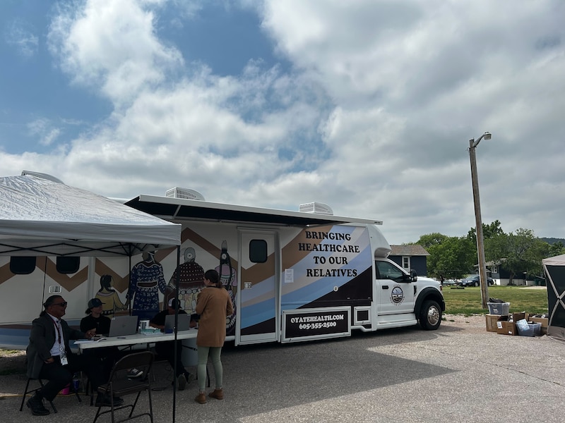People wait outside a mobile health clinic.