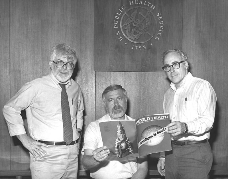 Three former directors of the Global Smallpox Eradication Program pose for a photo with a magazine.