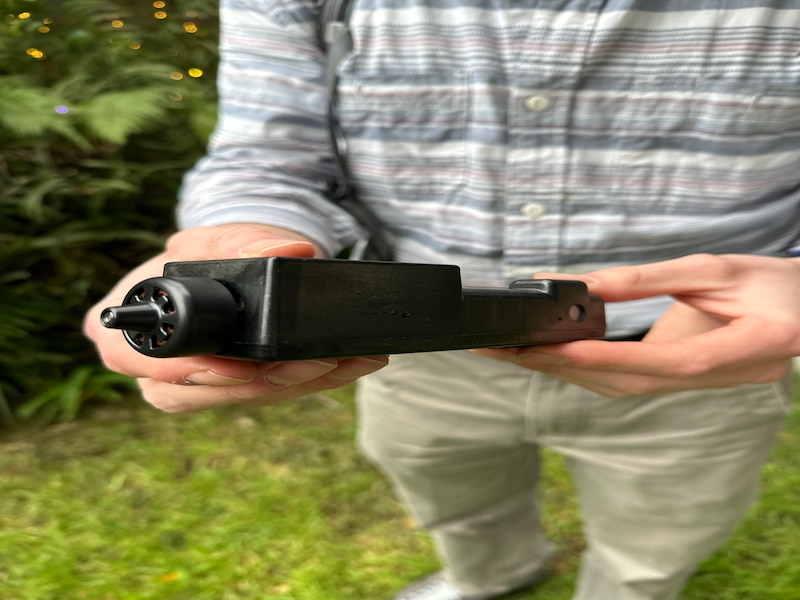 A man holds a small sensor to measure air quality.