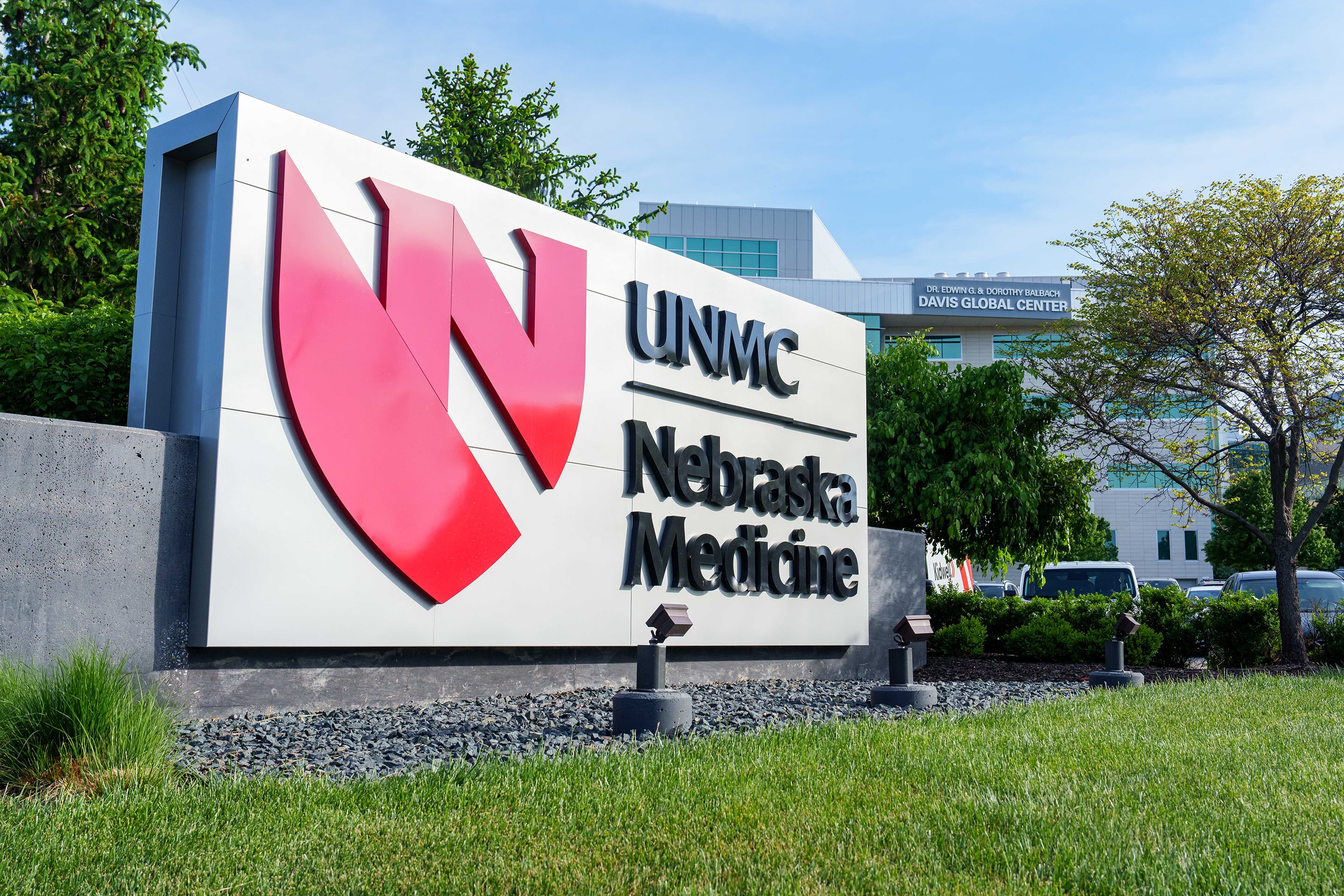 A photograph of a large University of Nebraska Medicine sign sitting outside of a large building on a sunny day.