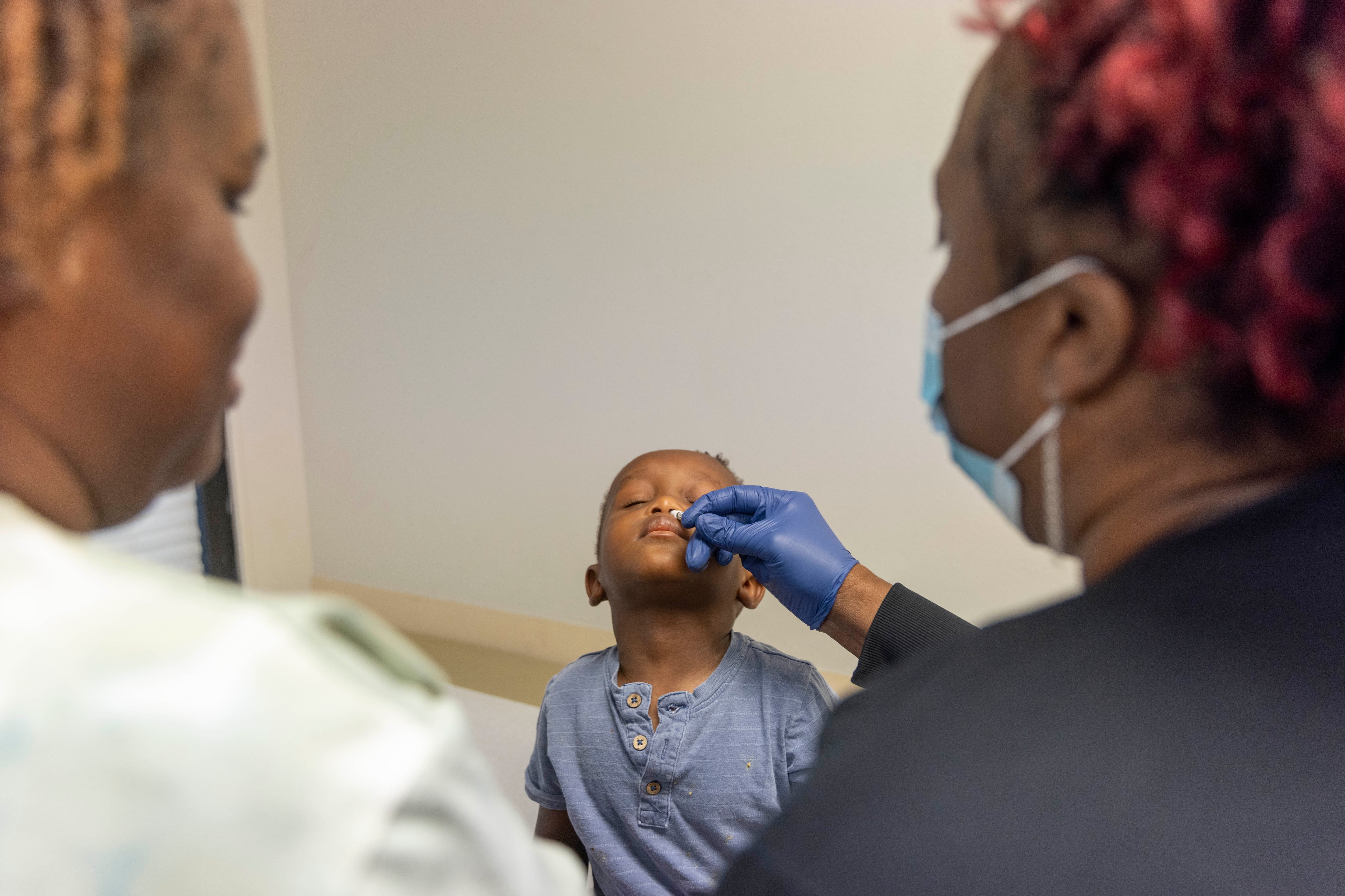 A boy gets a nasal spray vaccine for flu.