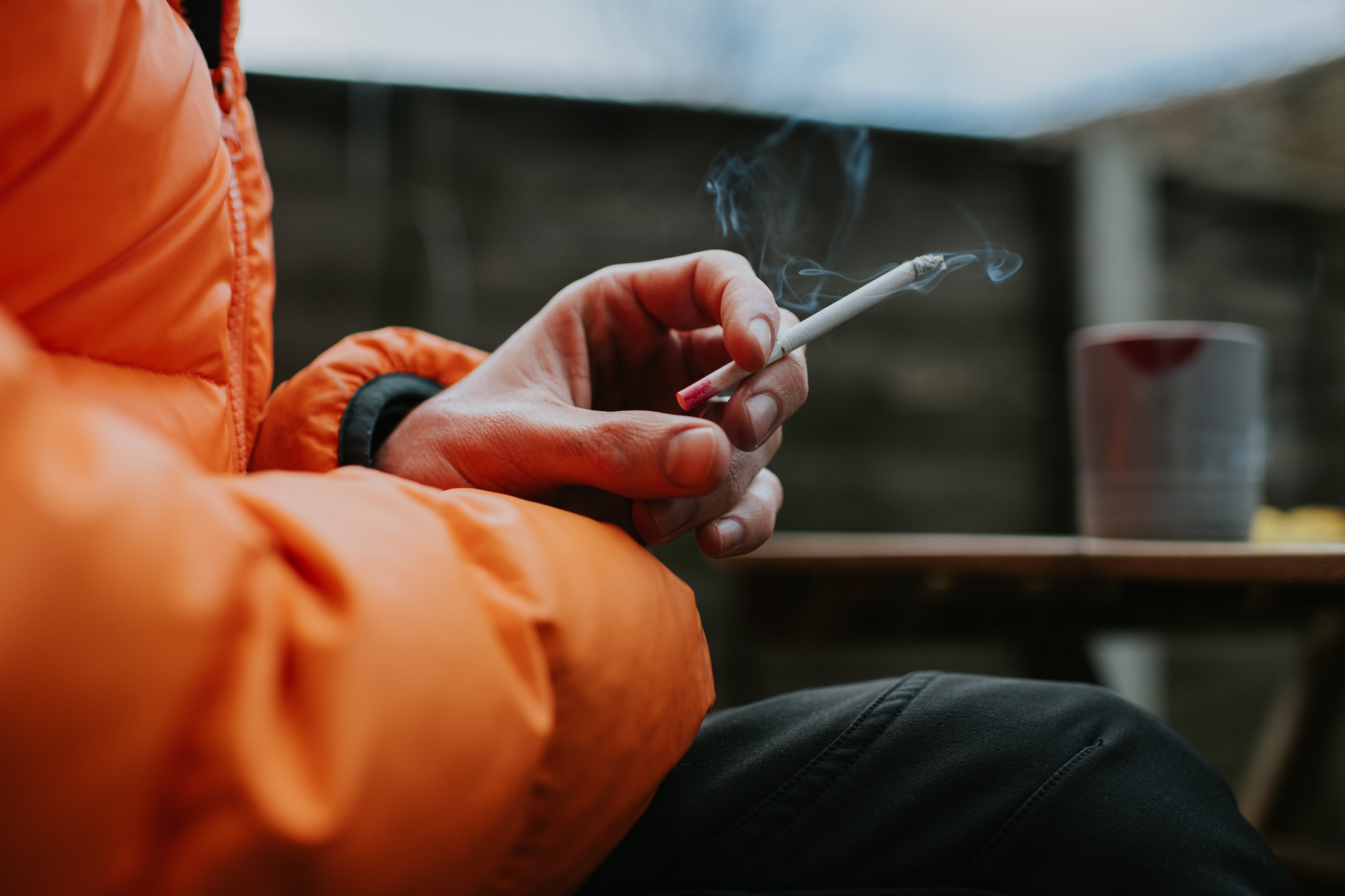 A hand holds a lit cigarette.