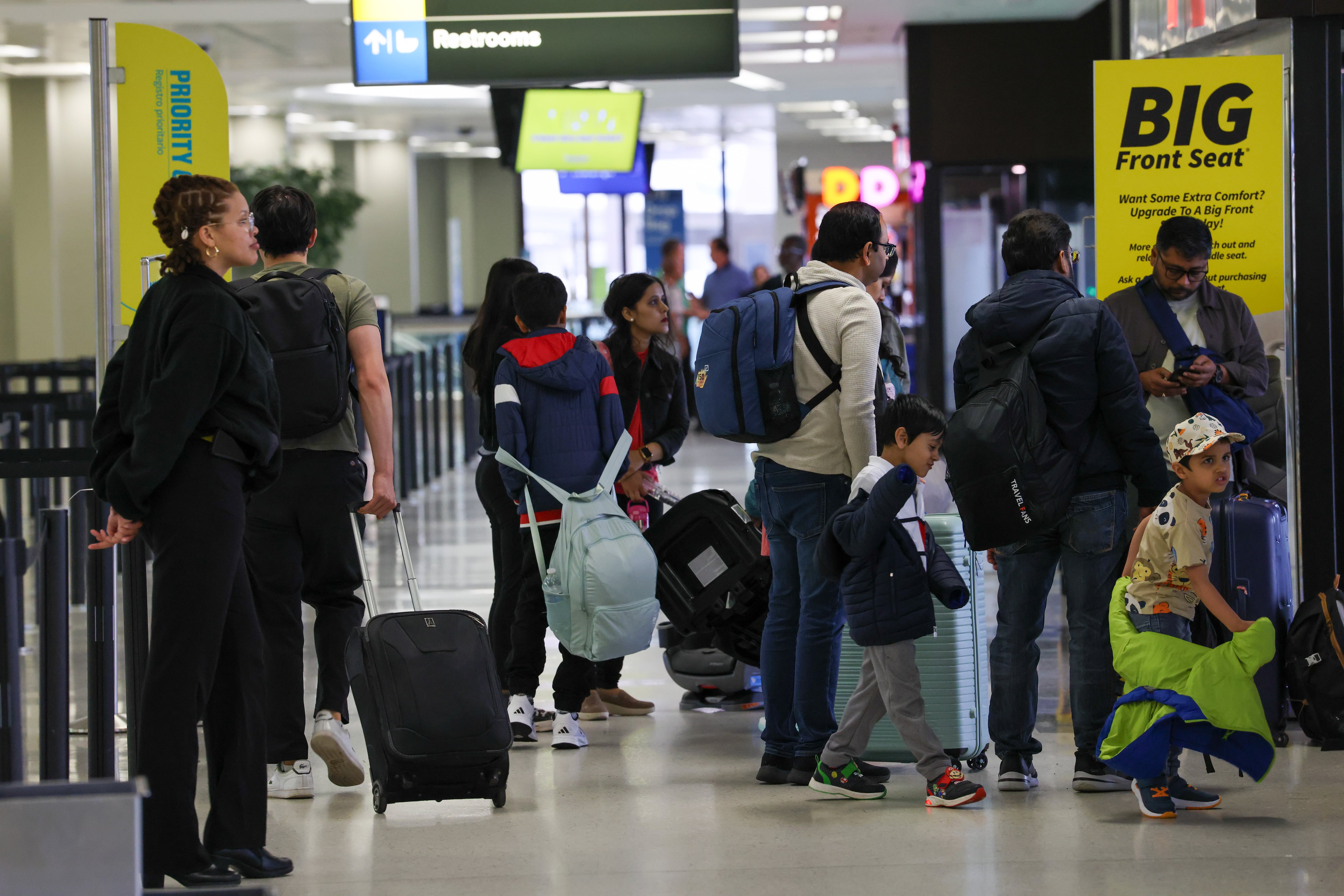 People stand in line inside an airport.