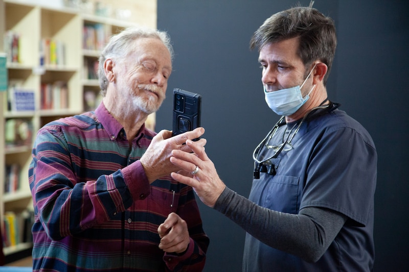 A patient and dentist look at a smartphone.
