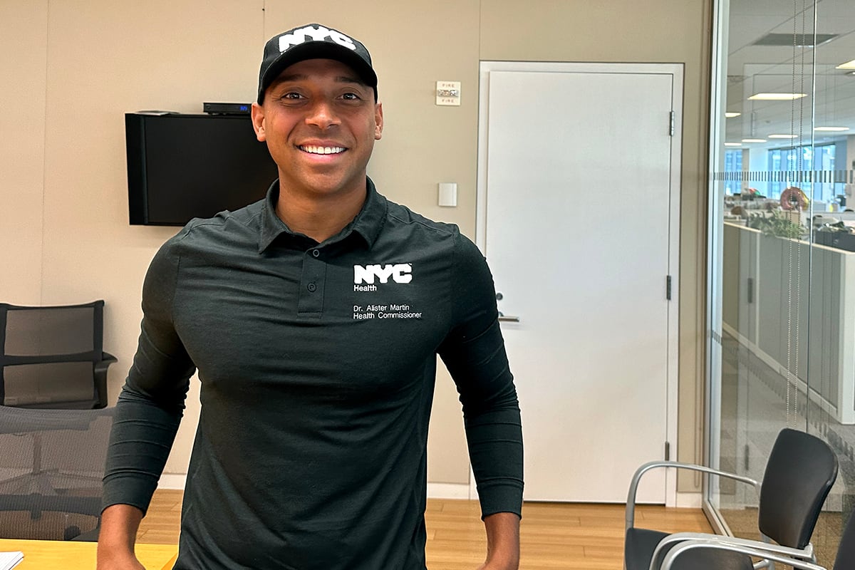 A man in a black shirt and cap poses for a portrait.