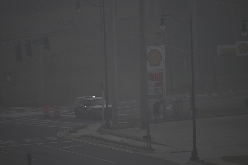 A vehicle and gas station sign are barely visible through smoke.