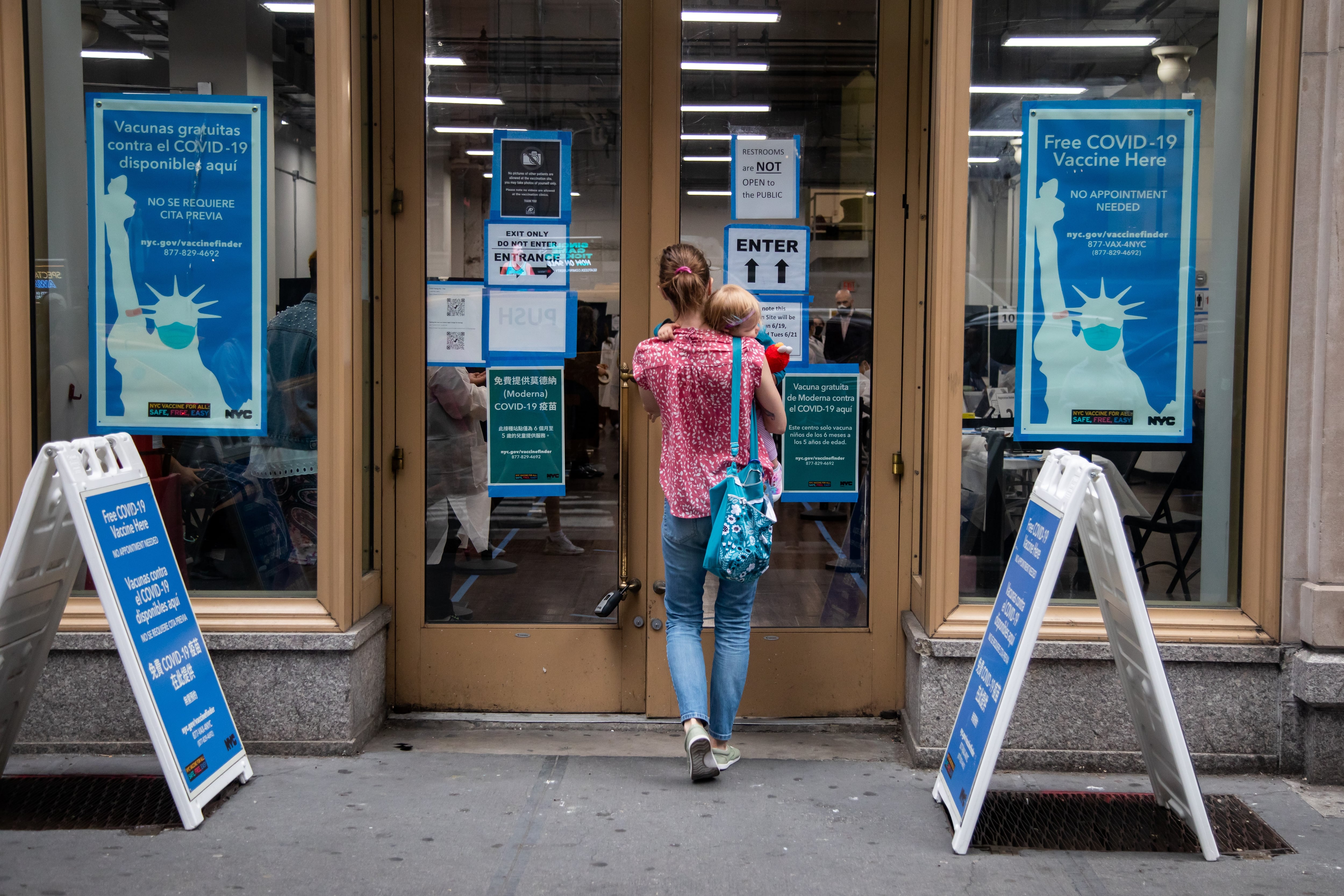 A woman carries a small child into a Covid vaccination center.