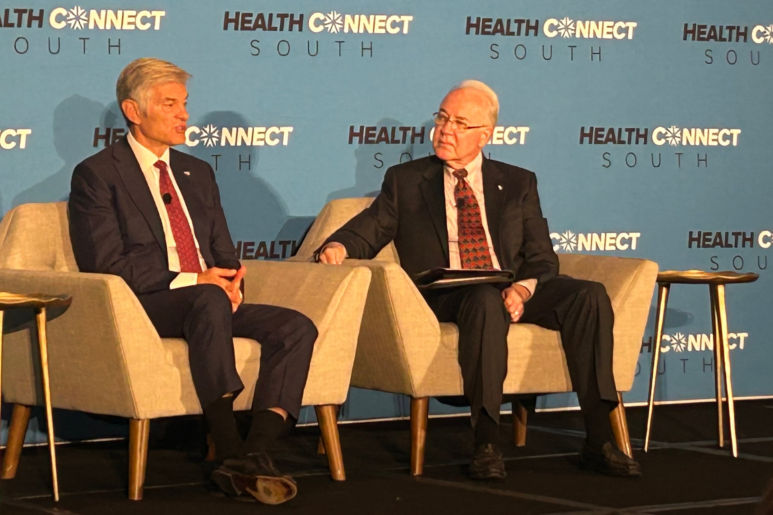 Mehmet Oz and Tom Price sit in chairs onstage.