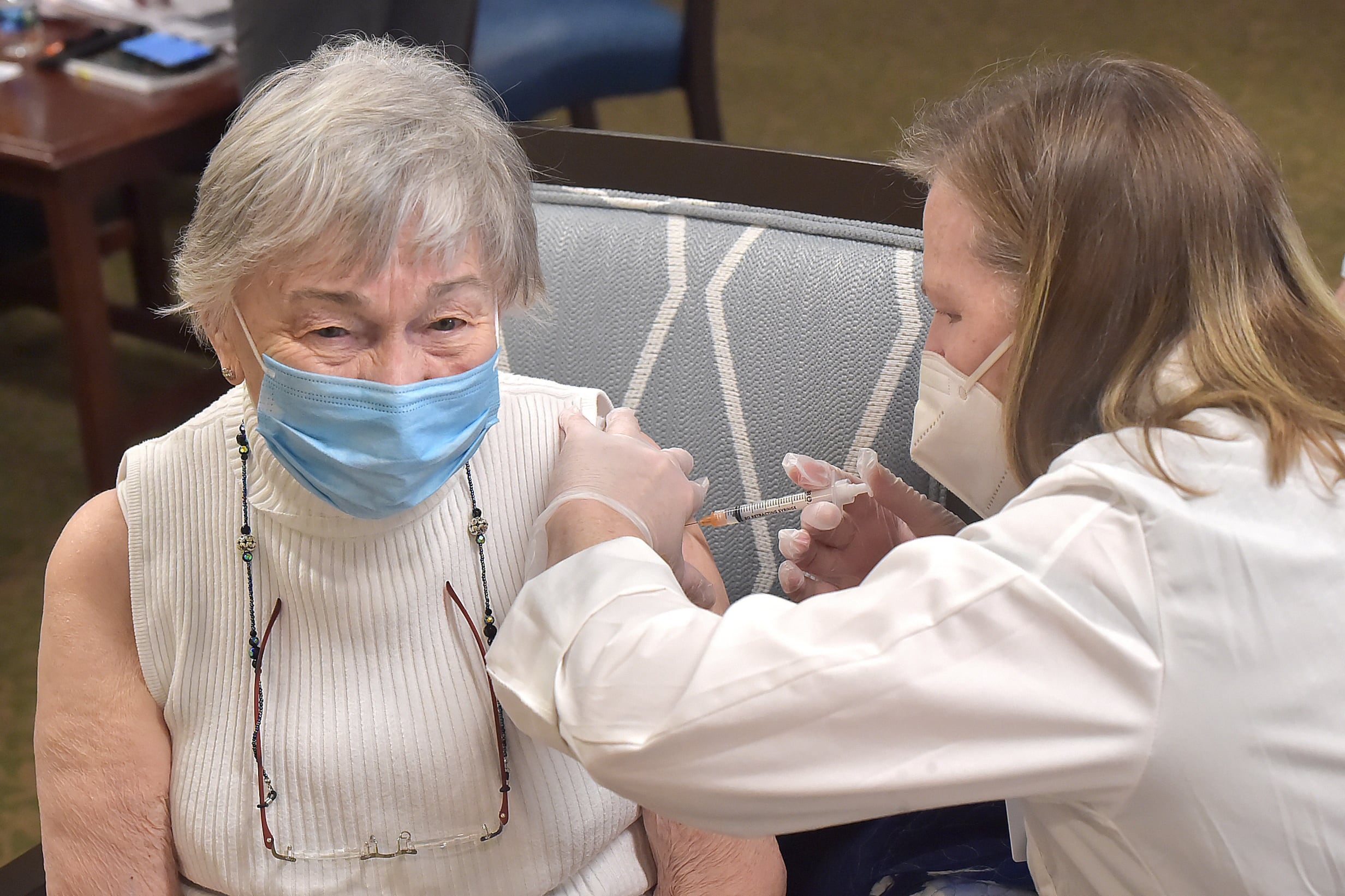 An older woman gets a vaccine shot in the arm.