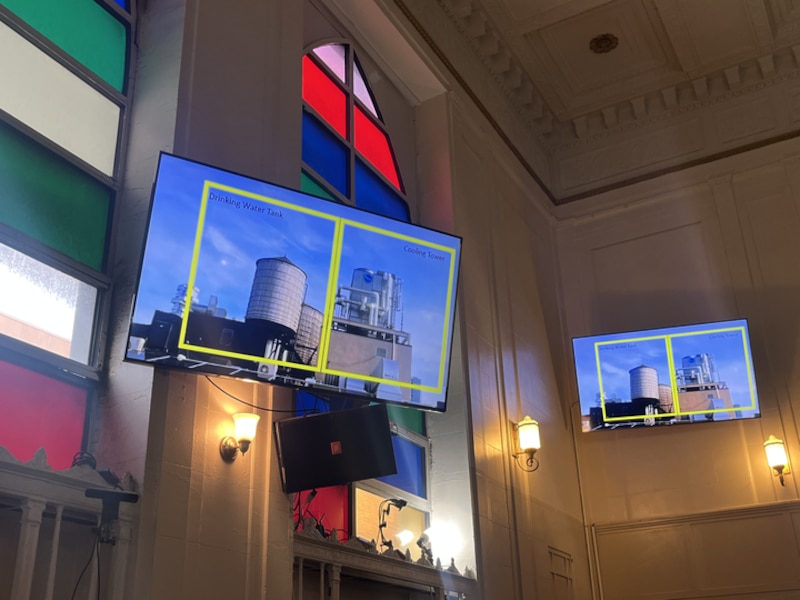 A slide on a projector shows the difference between a cooling tower and a drinking water tank.