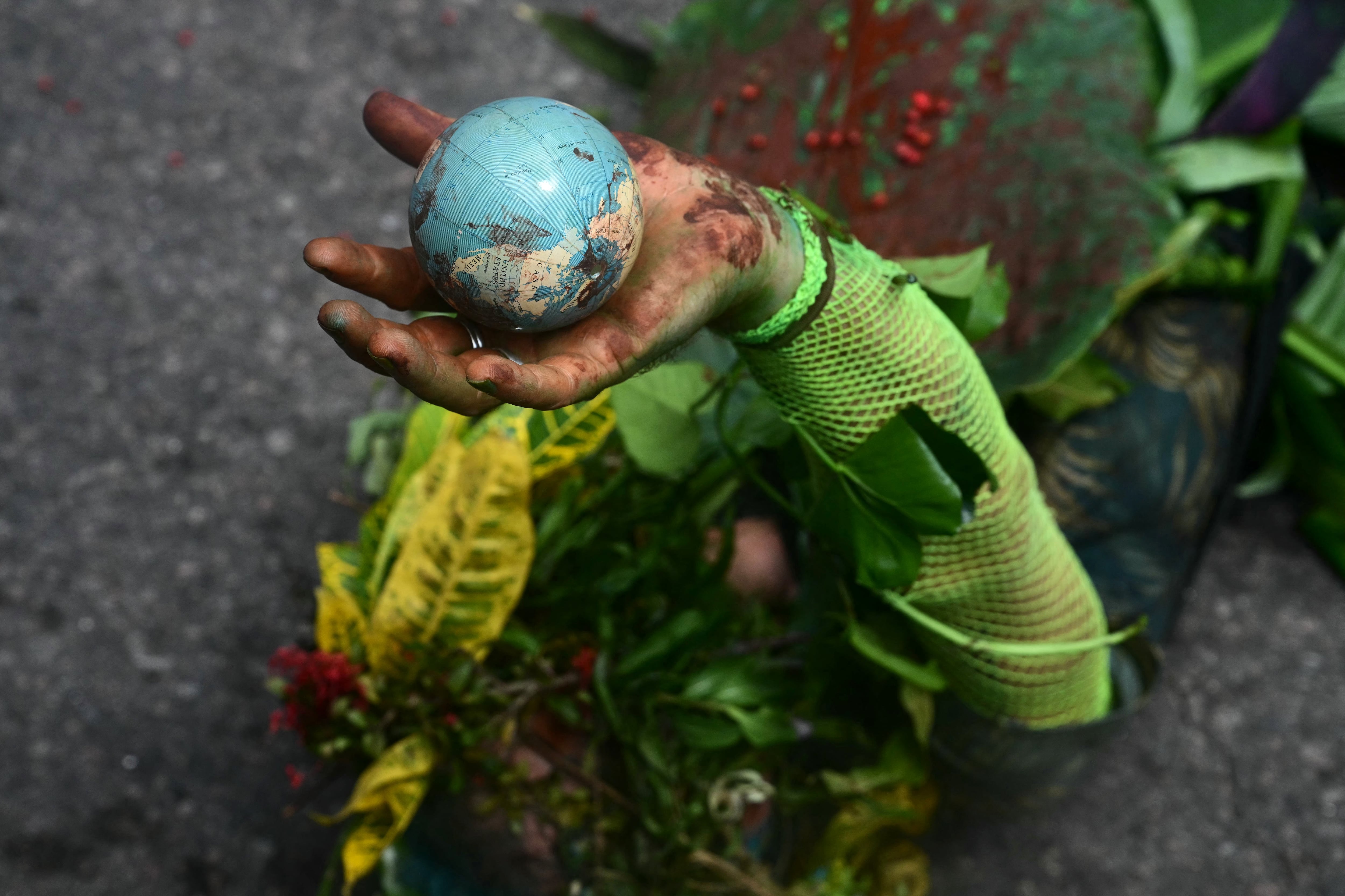 An Indigenous man performs lying on the ground while holding a globe in his hand.