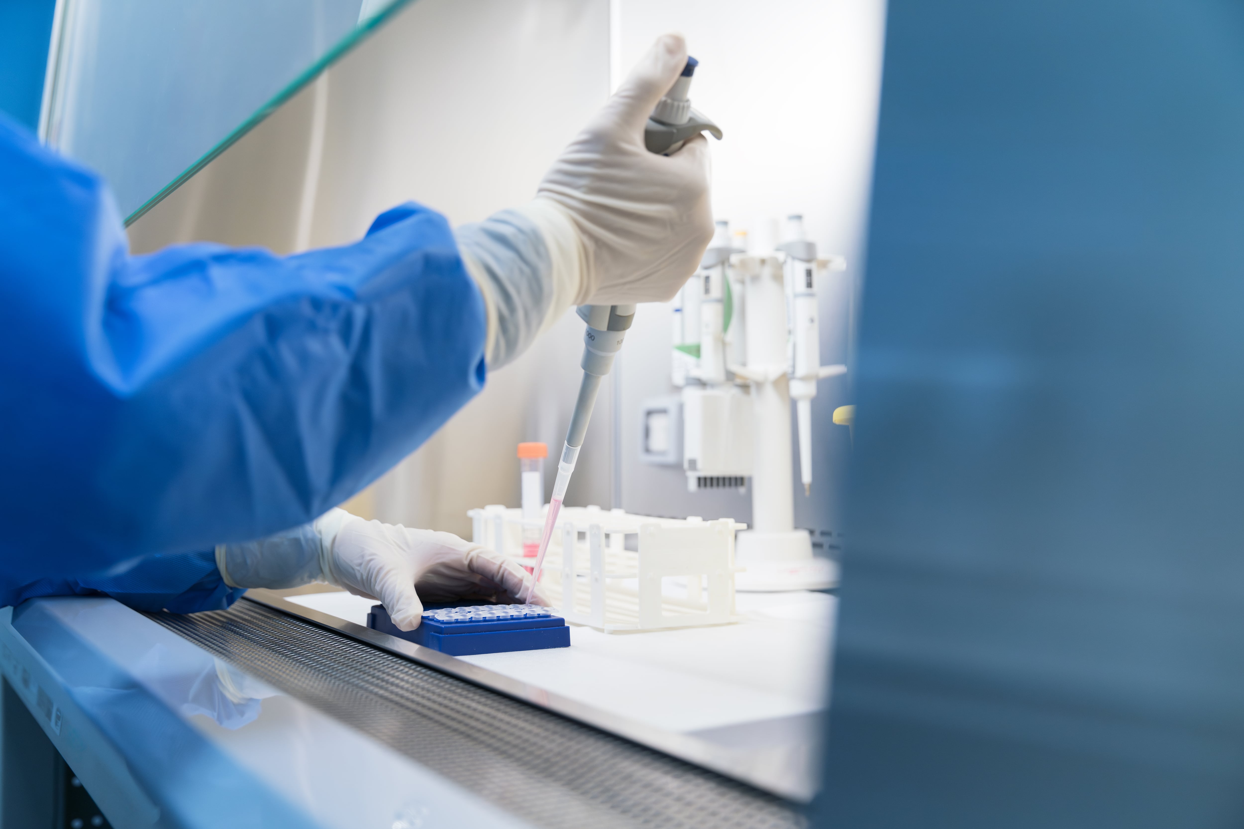 A lab worker holds a syringe.