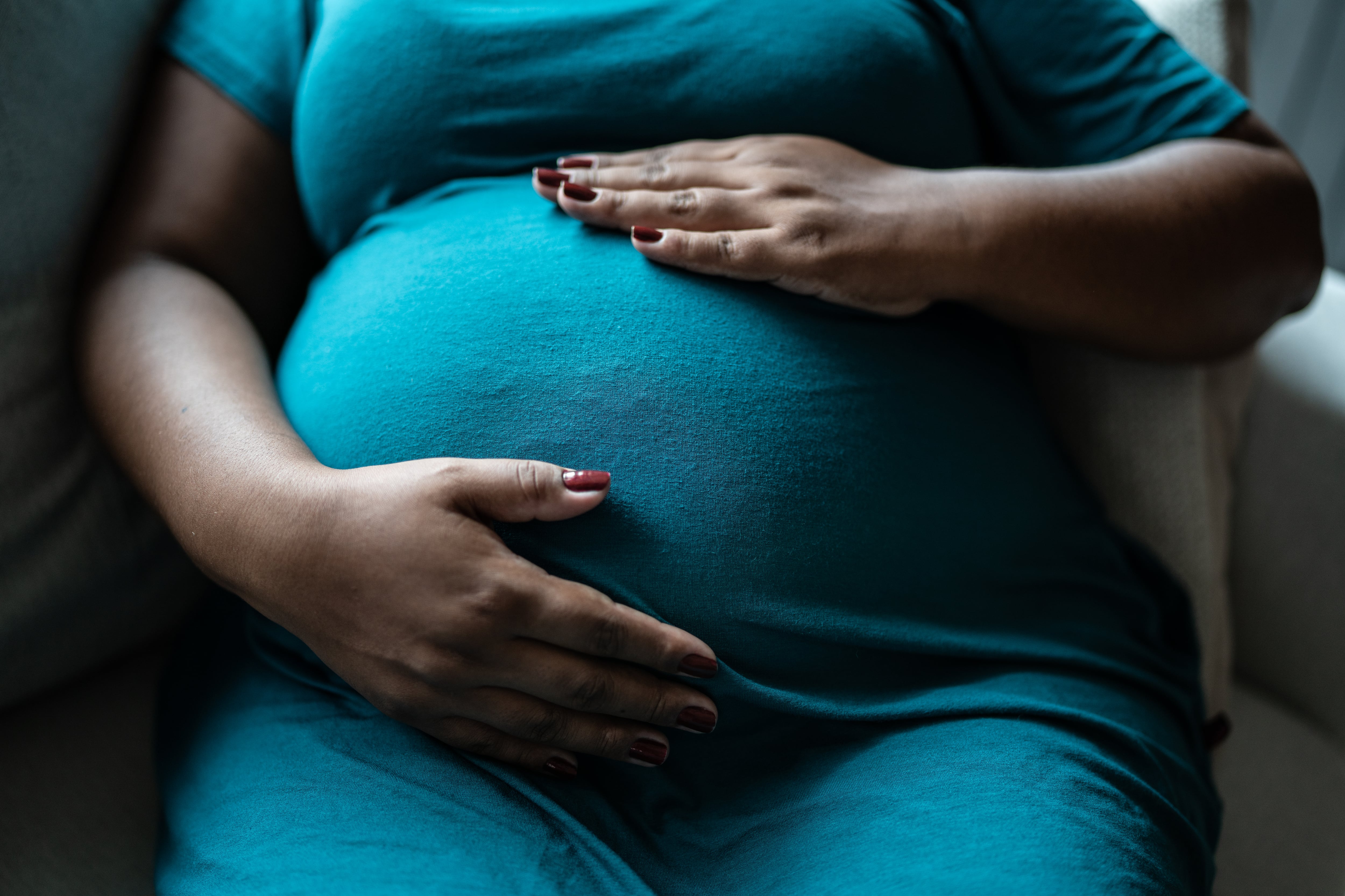 A pregnant woman touches her belly.