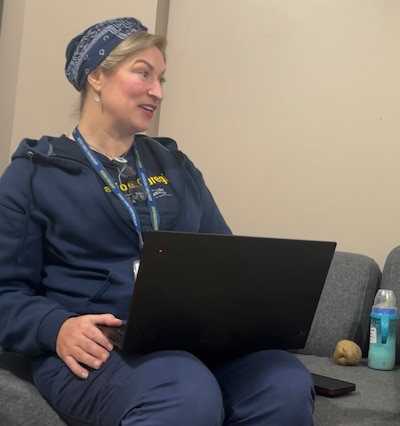 A nurse sits holding a laptop.