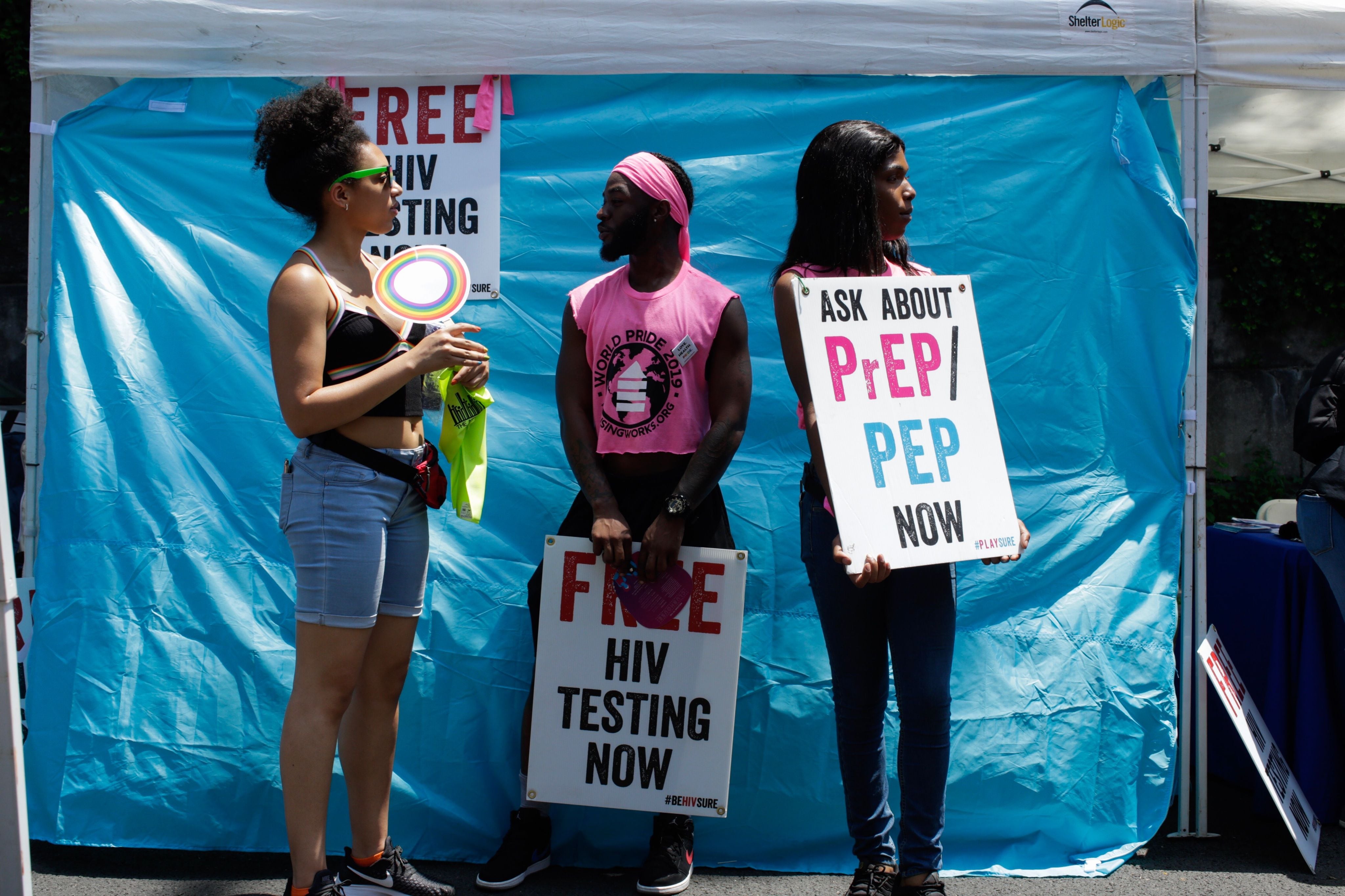 People attending parade hold signs promoting free HIV testing and "ask about Prep."