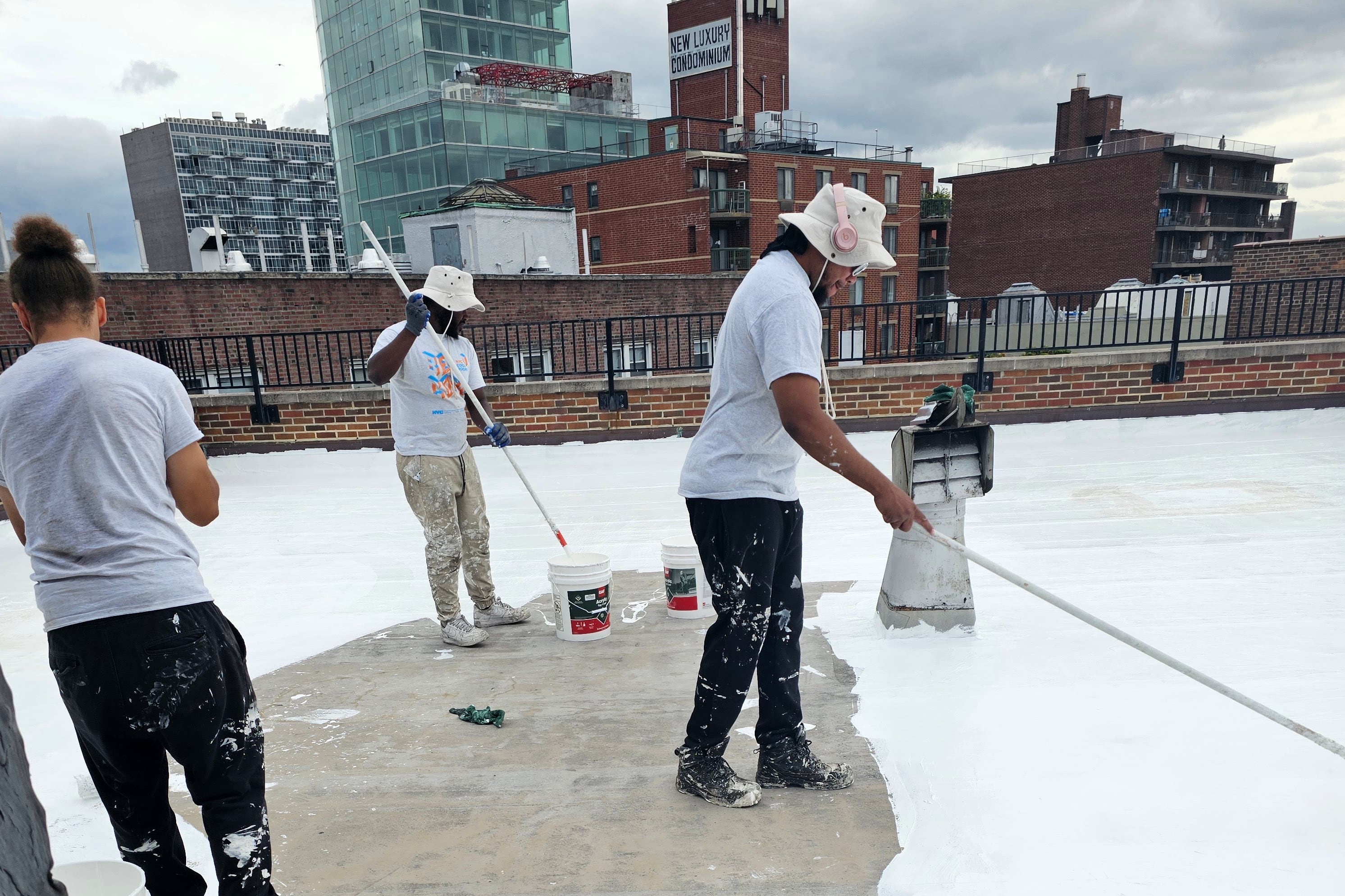 Workers apply a reflective white coating to a rooftop.