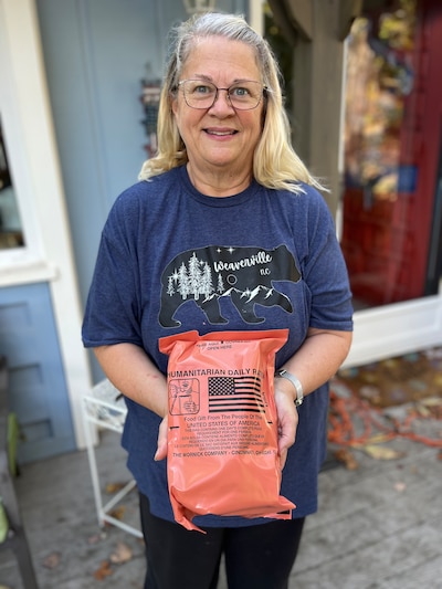 A woman holds a package of FEMA rations.
