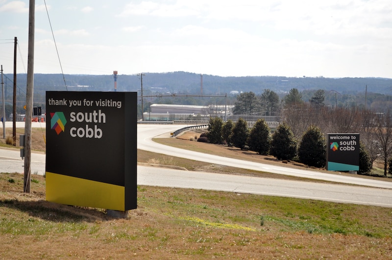 A curve in the road sits between two town signs.