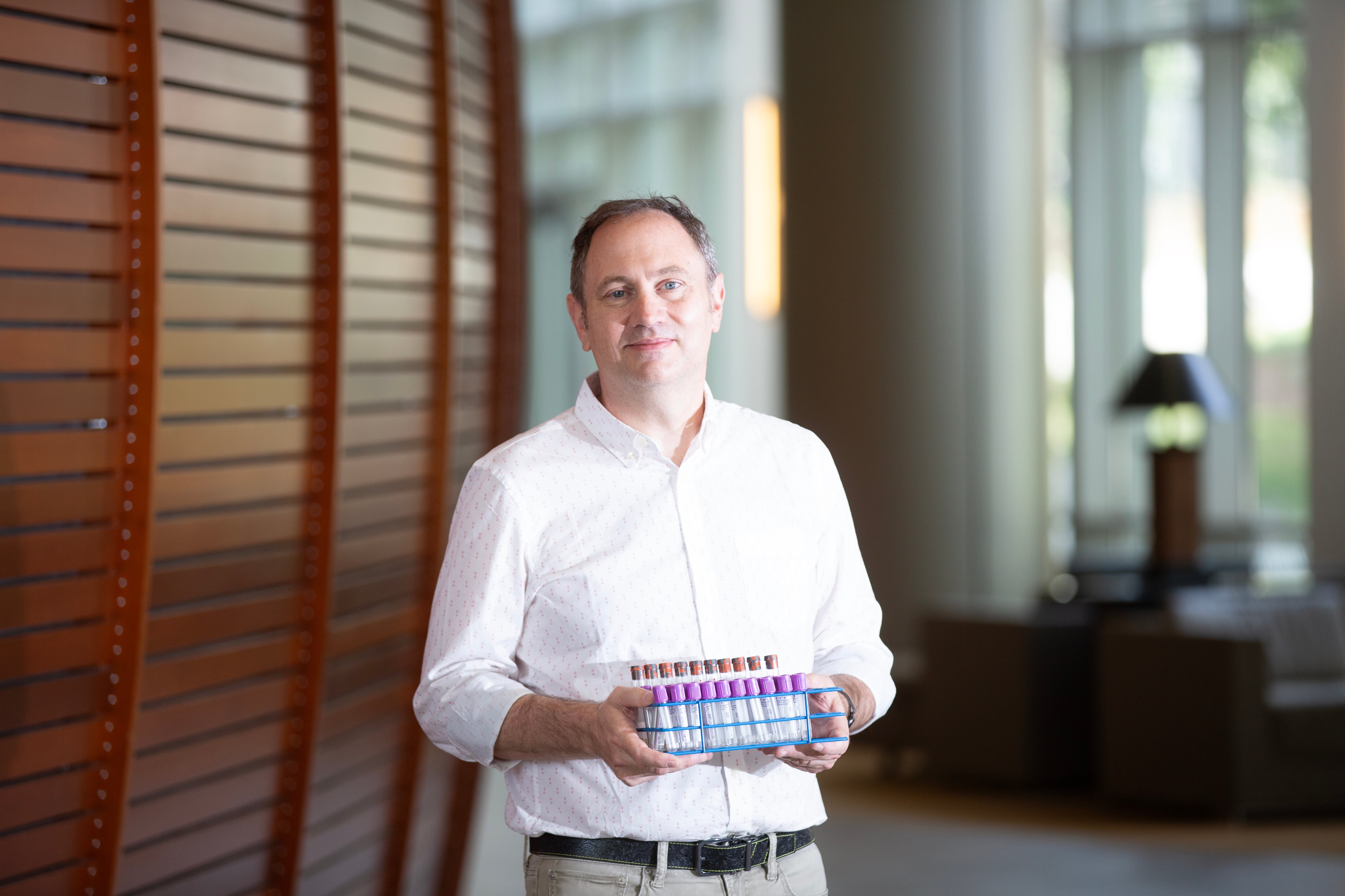 Patrick Sullivan holds a tray of test tubes.
