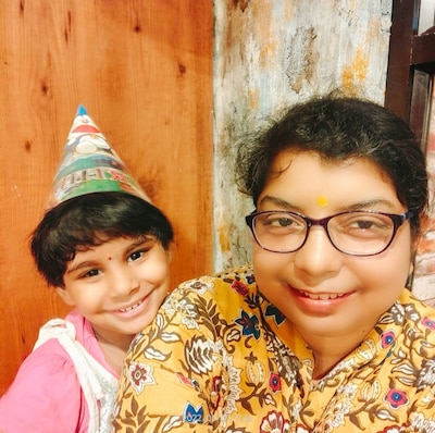 A child wearing a birthday party hat with her mother.