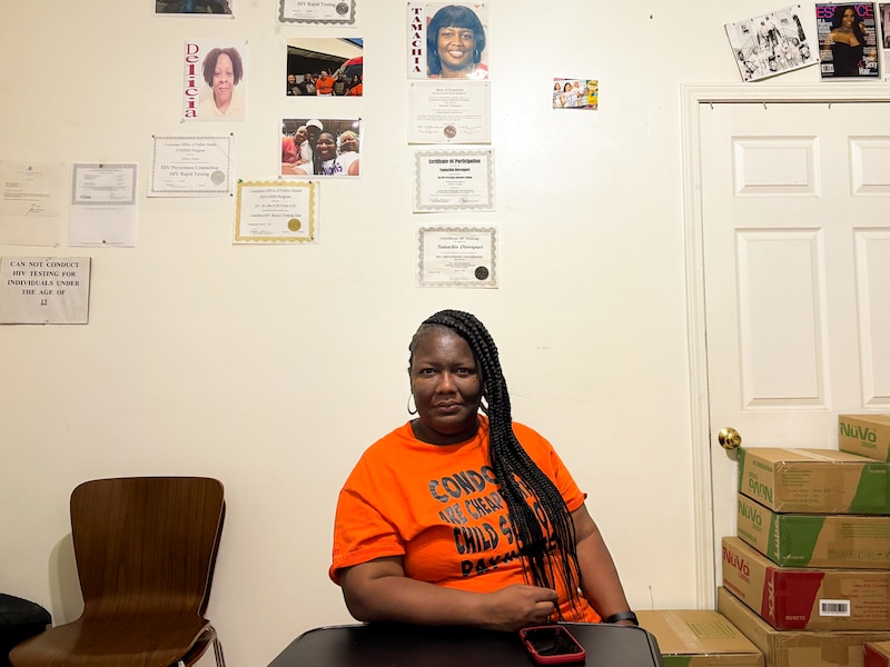 Tamachia Davenport sits in a room next to stacked boxes.