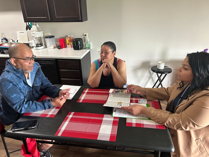 William Arce and his wife, Wanda Serrano, meet with Sau-Mei Ramos, a community health worker, around a kitchen table at their apartment.
