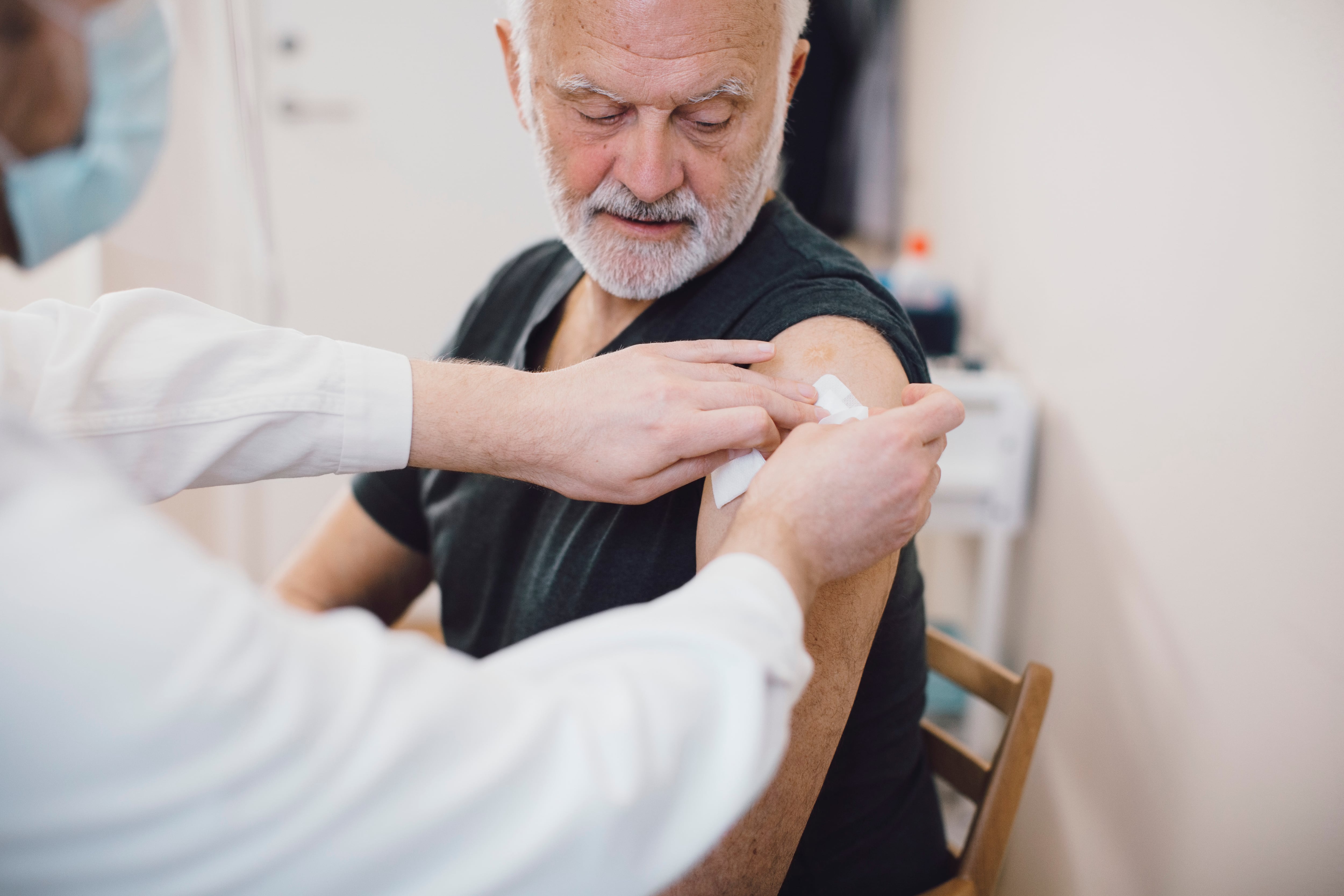 An older man gets a vaccine shot in the arm.