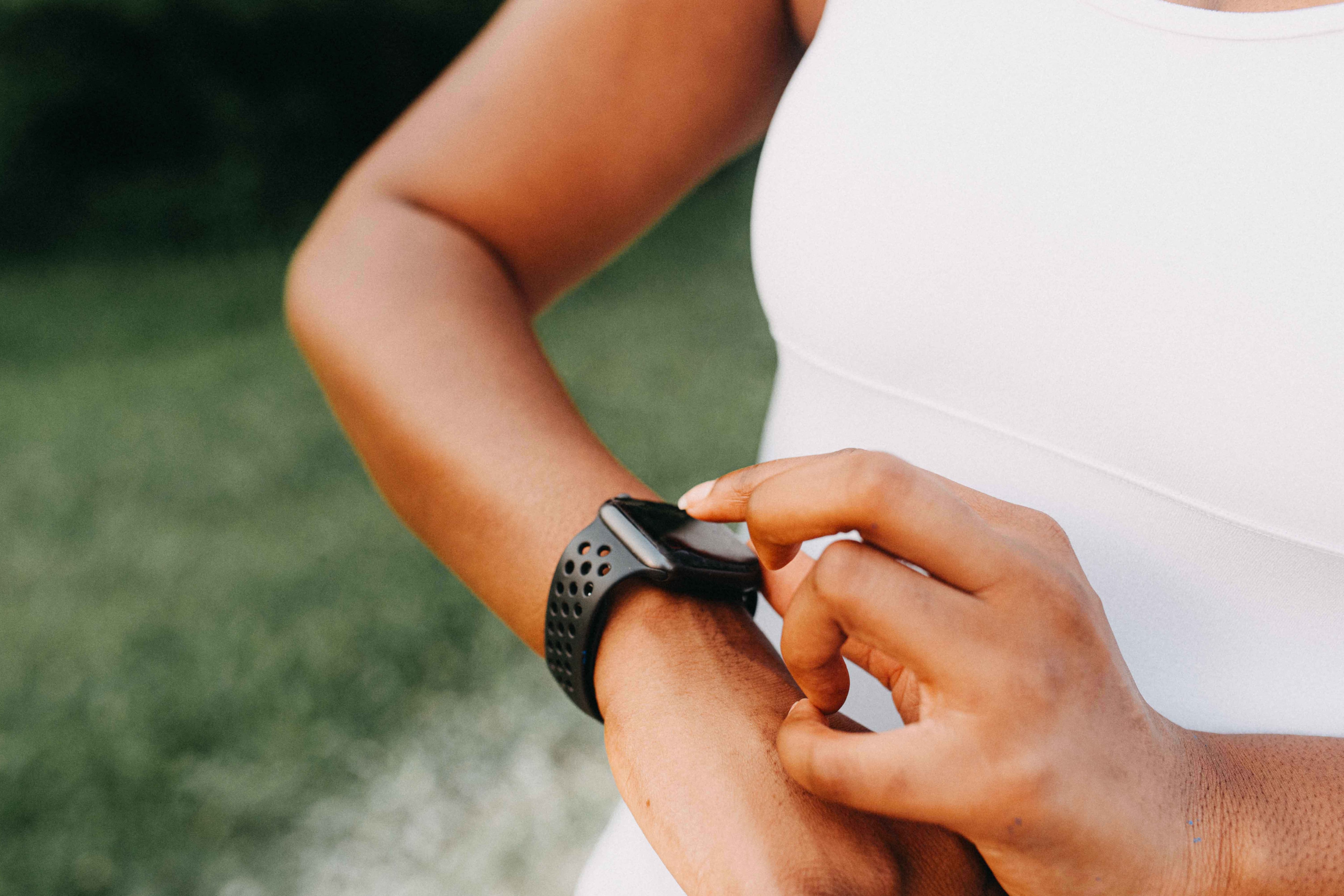 A woman touches a smart watch on her wrist.