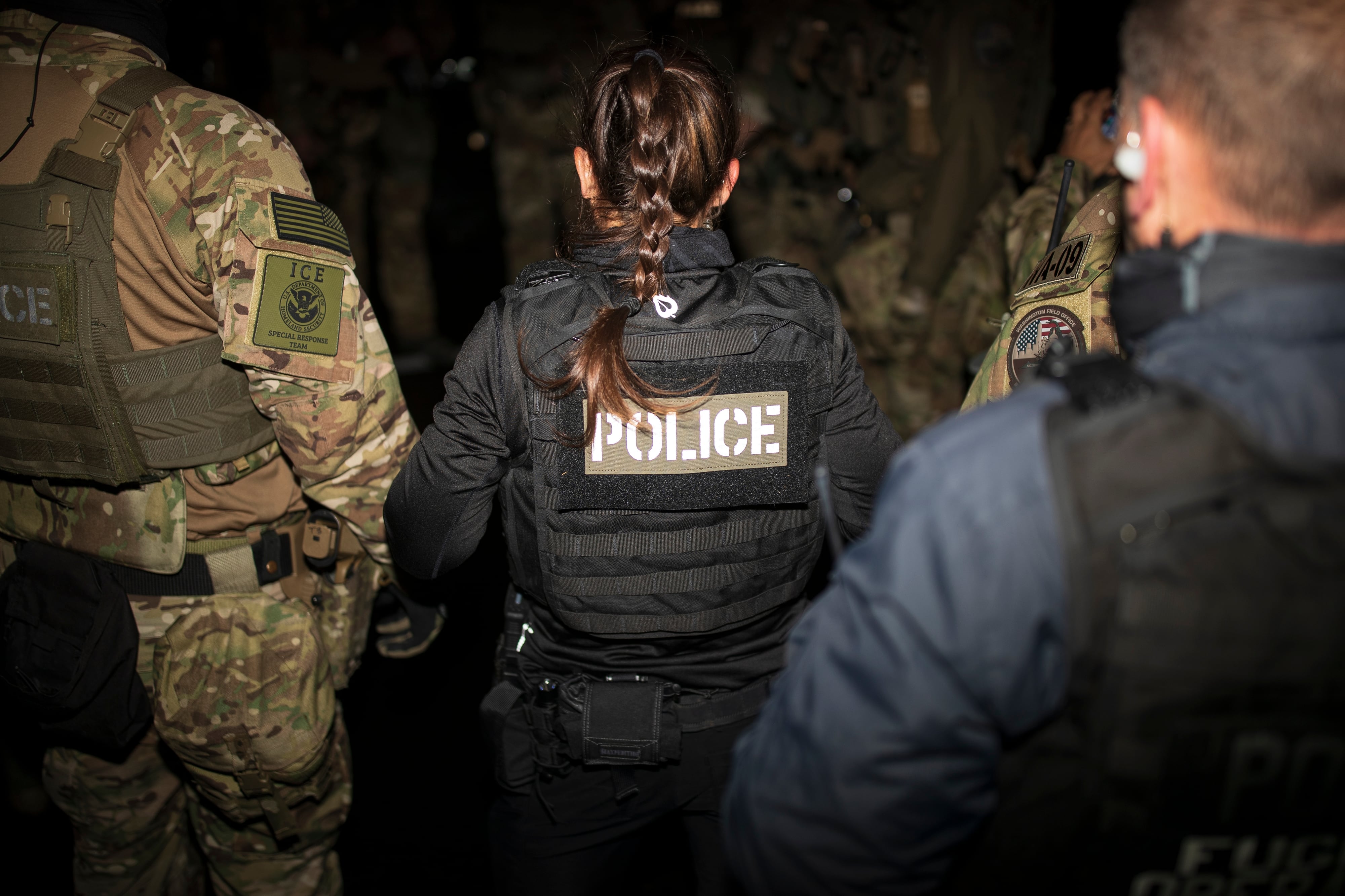 Immigration agents gather before a raid in the dark.