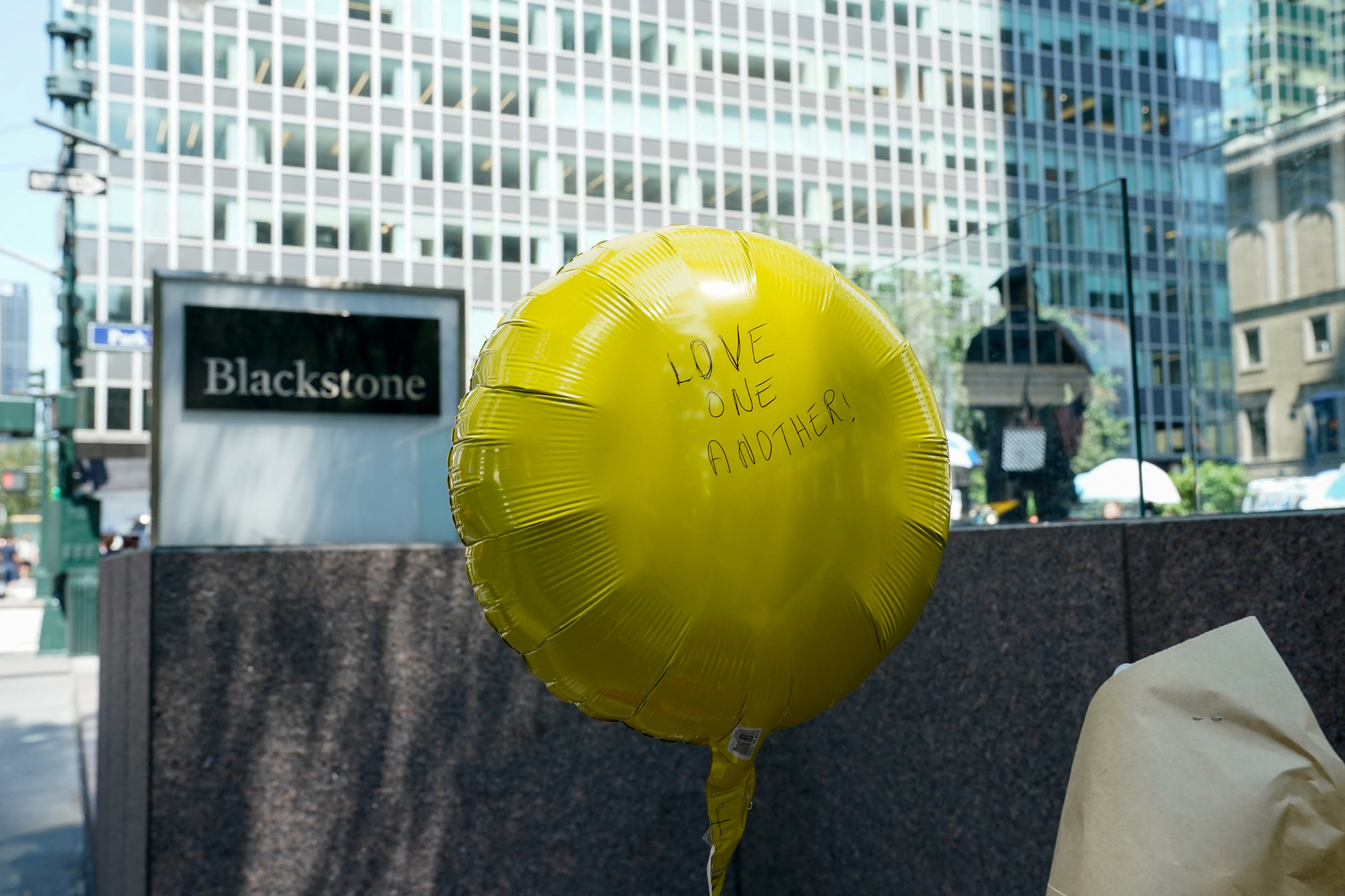 A yellow balloon reading "Love one another" is left outside the 345 Park Ave. building where a mass shooting took place on Monday in Midtown Manhattan.