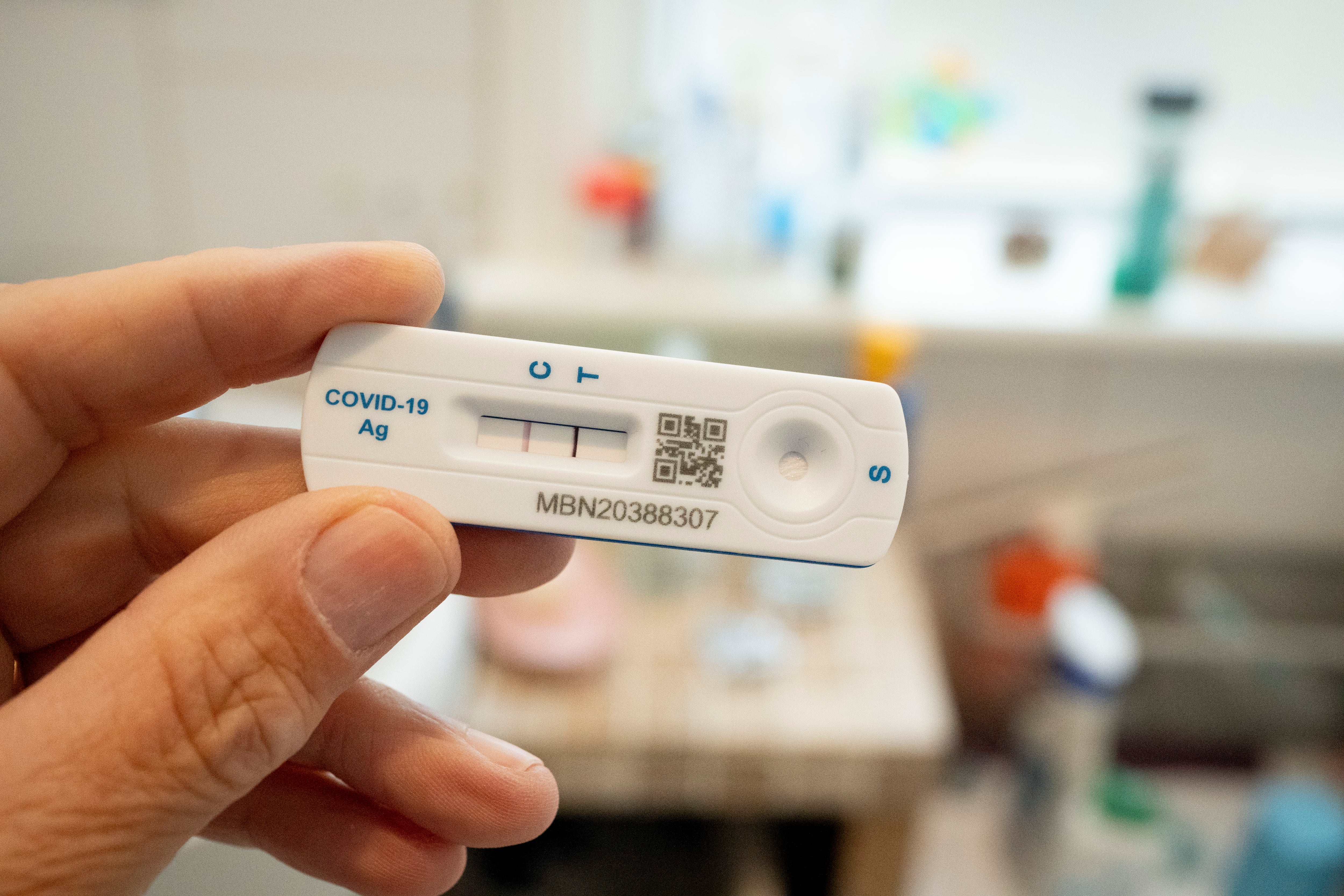 A hand holds up a Covid-19 home test showing a positive result.