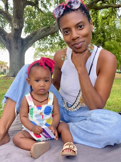 Marica Lowe sits on the ground outside with her 8-month-old baby girl.
