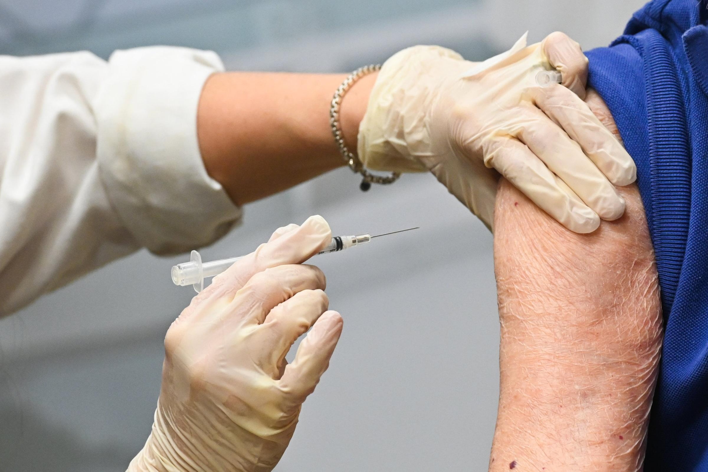 A health care worker gives a shot in the arm to a patient.