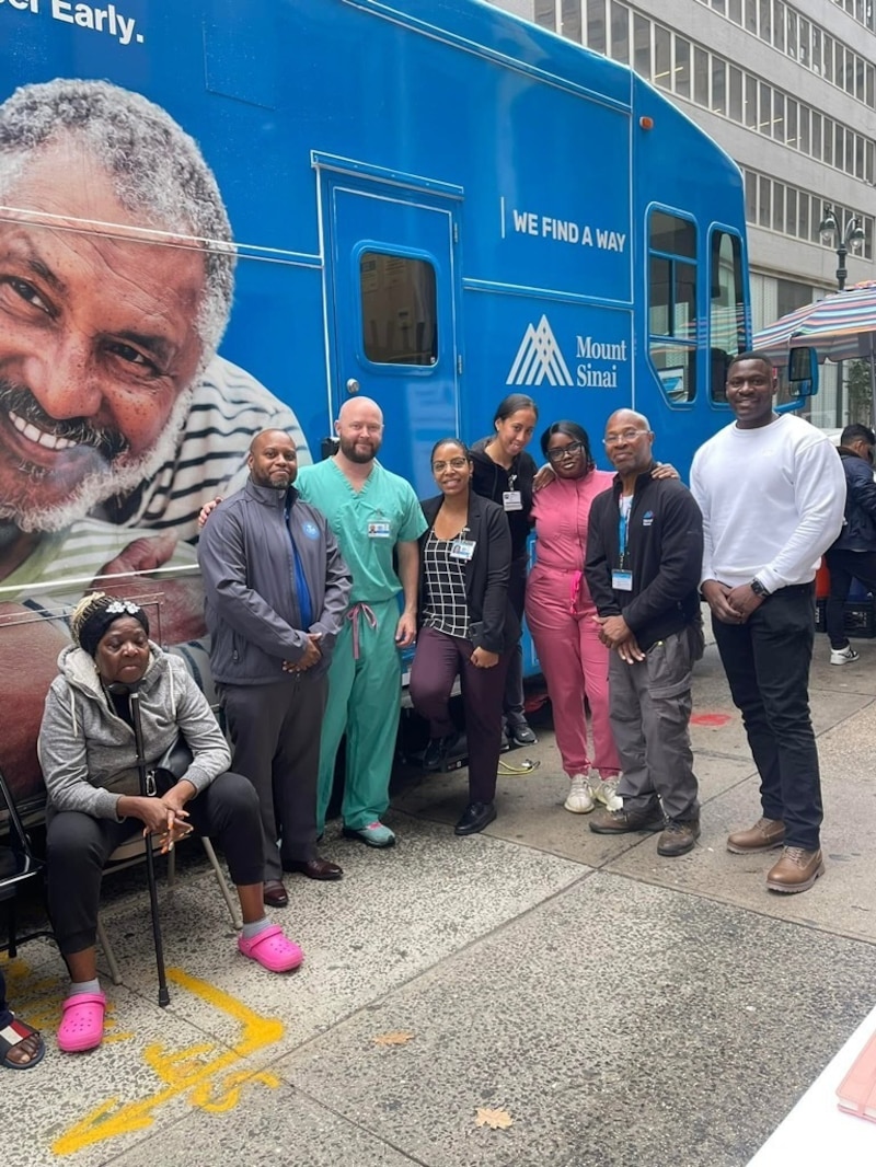 People stand in front of a hospital bus at a prostate cancer screening event.