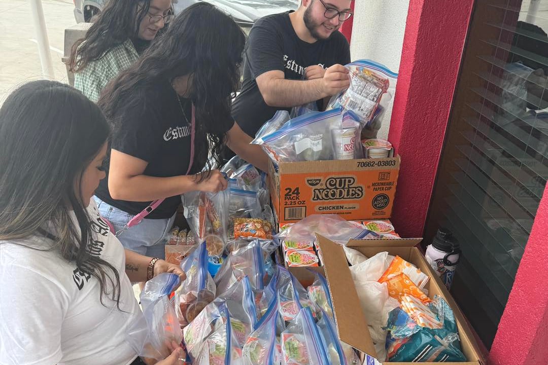 Four people sort through boxes of food on a table.