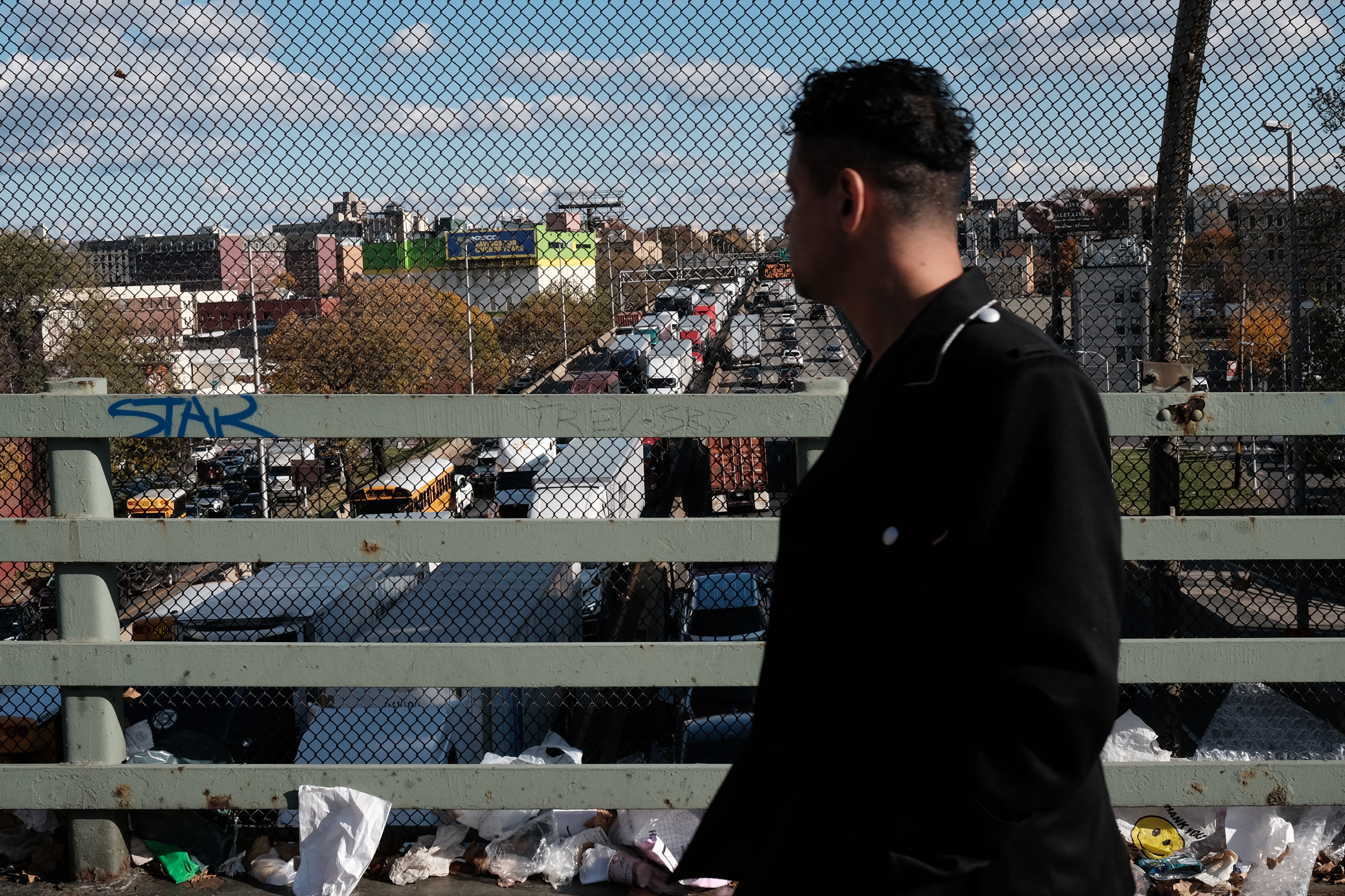 A man walks along an overpass above the Cross Bronx Expressway.